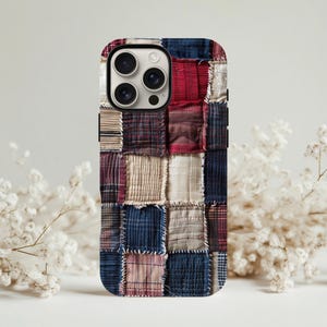 Könnte beinhalten: Eine Handyhülle mit Patchwork-Design. Die Hülle zeigt ein Muster aus verschiedenen Stoffquadraten in Rot-, Blau-, Beige- und Burgundertönen. Die Hülle hat eine glänzende Oberfläche und einen Kameraausschnitt.