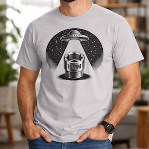 May include: Light gray t-shirt featuring a black and white graphic of a UFO beaming down on a 10mm socket wrench. The design includes a starry night sky background. The shirt is a short-sleeved crew neck.
