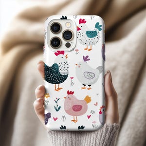 May include: White phone case with a repeating pattern of cartoon chickens in various colours. The chickens have different patterns, including polka dots and floral details. The case also features small hearts and flowers.