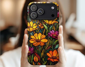 Puede incluir: Una funda de teléfono con un diseño floral colorido, con flores amarillas, naranjas y moradas con hojas verdes. La funda tiene un borde negro y cubre la parte trasera de un smartphone. El diseño recuerda a las vidrieras.