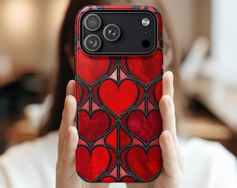 Puede incluir: Funda de teléfono roja con un diseño de corazones. La funda presenta un patrón repetido de corazones rojos con contornos negros, creando un efecto de vidriera. La funda tiene un acabado brillante y un módulo de cámara con tres lentes.