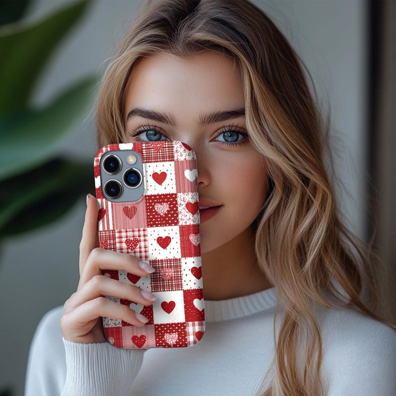 May include: A red and white patchwork phone case with heart patterns. The case features solid hearts, dotted hearts, and plaid squares. The case is designed for a smartphone with multiple camera lenses.