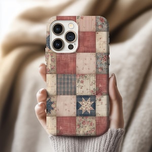 May include: A patchwork-style phone case featuring a variety of patterns and colors. The case has a mix of red, blue, and cream-colored squares with floral, striped, and plaid designs. The case is held in a person's hand.