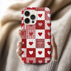 May include: A red and white patchwork phone case with heart patterns. The case features various heart designs, including solid hearts, polka dots, and floral prints. The case is designed to fit a smartphone.