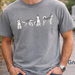 May include: Grey t-shirt featuring a graphic of a husky dog in various poses. The design includes a sitting, walking, howling, and standing husky. The word "Grey" is printed in the bottom right corner.