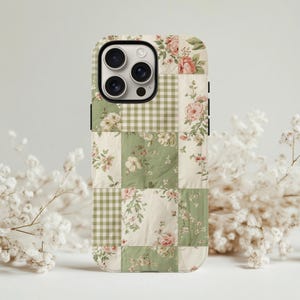 May include: A phone case with a patchwork design featuring floral patterns and gingham squares in shades of green, cream, and pink. The case has a black border and a camera cutout.