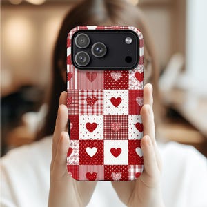 Puede incluir: Una funda de teléfono con estampado rojo y blanco con un diseño de patchwork con corazones. La funda tiene una variedad de patrones, incluyendo rayas, cuadros y estampados florales. La funda del teléfono se sostiene frente a una persona.