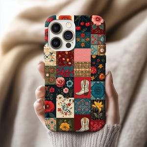 May include: A colorful phone case featuring a patchwork design with floral and cowboy boot motifs. The case has a square pattern with various colors, including red, blue, and yellow. The case is held in a person's hand.