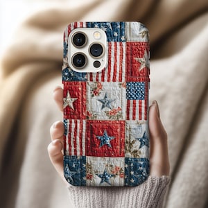 May include: A phone case with a patchwork design featuring red and white stripes, blue stars, and floral accents. The case has a quilted appearance, evoking a patriotic theme.
