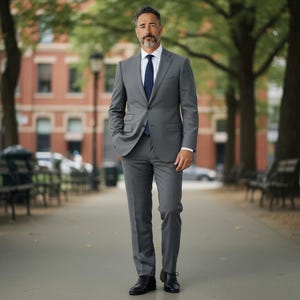 May include: A charcoal gray two-piece suit consisting of a single-breasted blazer with notched lapels and matching trousers. The suit is worn with a crisp white collared dress shirt, a solid navy blue necktie, and polished black leather dress shoes.