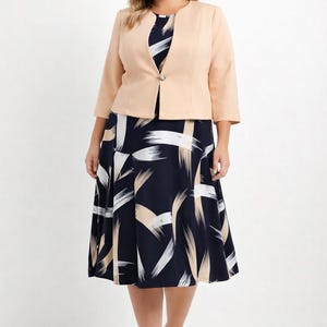 Könnte beinhalten: Pfirsichfarbene Jacke mit Dreiviertelärmeln über einem marineblauen Kleid mit weißem und beigem Pinselstrichmuster. Das Kleid reicht bis zu den Knien, kombiniert mit passenden Absätzen.