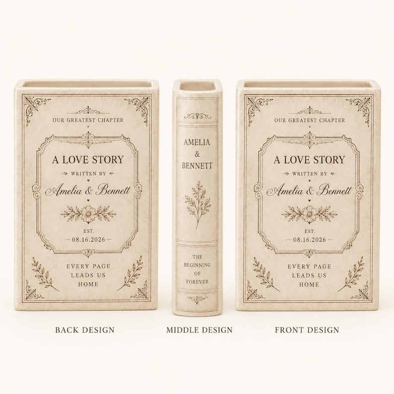 May include: A cream-colored ceramic book-shaped vase featuring black text and floral line art. The front and back display 'A LOVE STORY', 'Amelia & Bennett', and '08.16.2026'. The spine reads 'AMELIA & BENNETT' and 'THE BEGINNING OF FOREVER'.