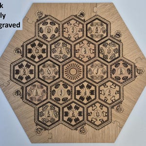 May include: An oak board game, fully engraved with a hexagonal layout. Each hexagon contains detailed illustrations, including numbers and resource symbols, with a sun design at the centre. The text "Oak Fully Engraved" is visible.