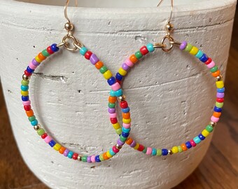Può includere: Un paio di orecchini a cerchio con perline arcobaleno e ganci dorati.