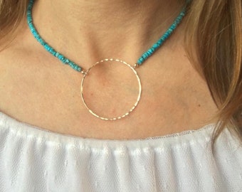 Può includere: Una collana di perline turchesi con un ciondolo circolare dorato.