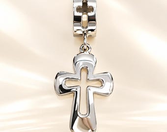 May include: A polished silver-tone metal pendant featuring a cross shape with a hollow center. The pendant is attached to a cylindrical bail that also contains a small cutout cross design, creating a cohesive and reflective metallic piece.