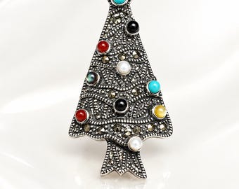May include: A silver-toned brooch shaped like a Christmas tree, featuring a textured surface inlaid with small marcasite stones and decorated with various colorful round cabochon gemstones including turquoise, red, black, white, and yellow.