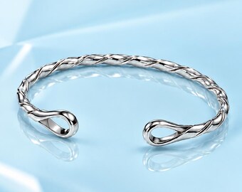 May include: A silver-toned cuff bracelet featuring a twisted rope-like texture throughout the band. The bracelet has an open design with two rounded, loop-shaped terminals at each end, creating a continuous metallic aesthetic.