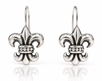 May include: A pair of silver-toned earrings featuring a fleur-de-lis design. Each earring has a polished finish with a central horizontal band decorated with small, raised spherical beads and a curved hook for attachment to the ear.