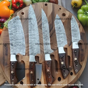 May include: A collection of six kitchen knives featuring patterned steel blades and dark wooden handles. The knives are presented on a wooden chopping board with a circular design. The handles have decorative metal accents. The text "VIKING EXPERT" is visible.
