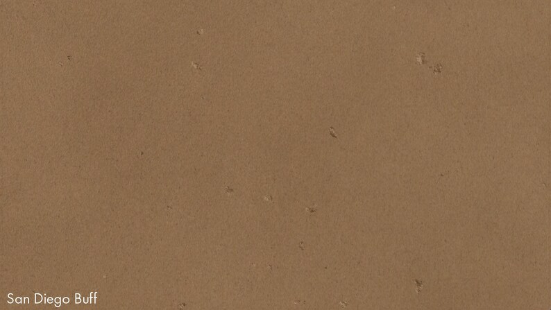 The image is a close-up of a brown surface, possibly a wall or a piece of paper, with small white specks or specks of color scattered across it.
