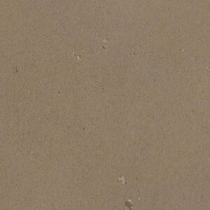 The image is a close-up of a textured surface, possibly a piece of paper or a fabric, with small white specks scattered across it.