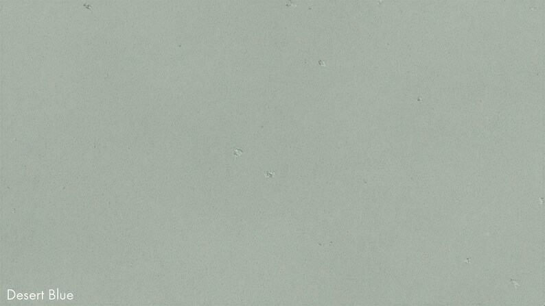 The image is a plain, light green color with small white specks scattered throughout, resembling a desert landscape.