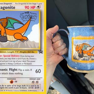 以下が含まれることがあります： ポケモンカードのカイリューをモチーフにした、オレンジ色のドラゴンが黒いバッグを運ぶ手描きのイラストが施された青い陶器製のマグカップ。マグカップは青い斑点模様の釉薬で仕上げられており、イラストの周りには長方形の枠が描かれています。