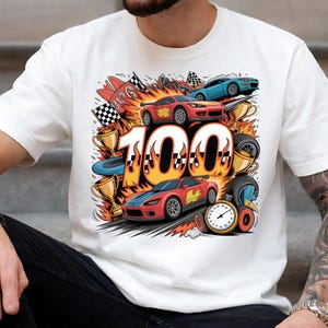 Puede incluir: Camiseta blanca con un diseño colorido de carreras. El diseño incluye coches de carreras, banderas a cuadros, trofeos y el número "100" con un efecto de llama. También se incluye un velocímetro.
