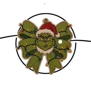 May include: An embroidered patch shaped like a green bow featuring a grumpy character wearing a red and white Santa hat. The bow is decorated with colorful Christmas light bulbs. The text THEVELOCITYSTITCH is printed at the bottom.