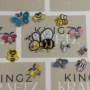 May include: A selection of embroidered insect patches. The patches depict bees and butterflies in bright colours, including yellow, blue, pink, and black. The patches are displayed on a light beige background.