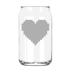 May include: A clear glass can-shaped drinking glass with a gray pixelated heart design. The glass has a wide mouth and a slightly curved body, suitable for various beverages. The heart is centered on the glass.