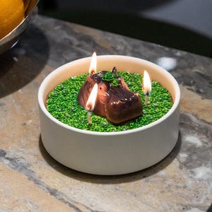 A handcrafted Realistic Cute Hippo Candle Bowl featuring a cute hippo animal emerging from a green wax pond and lit with three flames, a novelty whimsical handmade candle that makes a dlegant  home décor accent and a perfect gift for holidays and hippo candle lovers.
