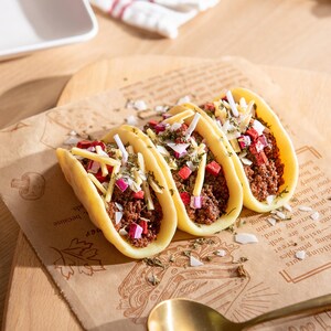 Close-up of realistic taco candles crafted from soy wax, featuring detailed shells filled with ground beef texture, shredded cheese wax melts, onions, and herbs. Handmade novelty food candle gift for taco lovers