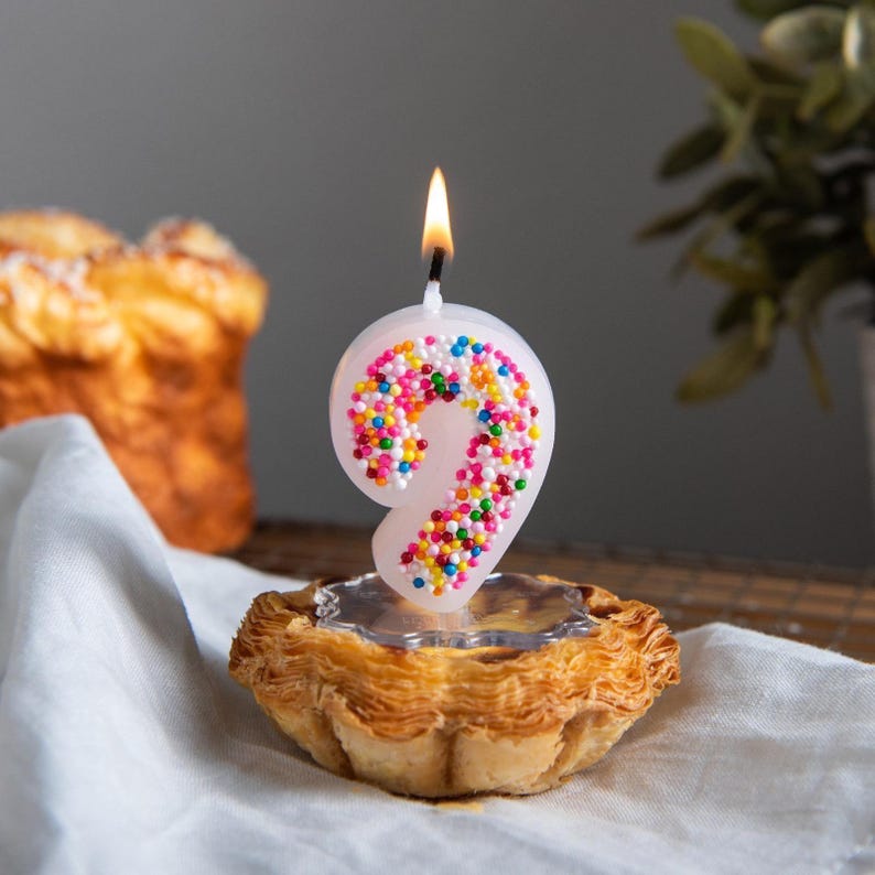 Burning number 9 sprinkle candy candle with bright pastel dots, displayed as a joyful birthday cake topper candle.