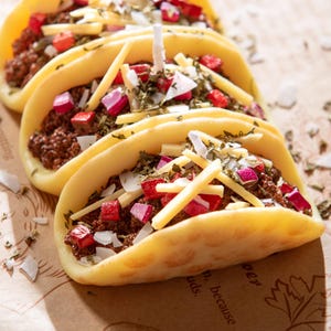 Macro close-up of hand-poured taco candles with realistic soy wax shells, ground beef texture, red onions, herbs, and shredded cheese wax melts. Unique novelty candle gift for taco lovers and perfect mexcian gift decoration candle birthday gifts.