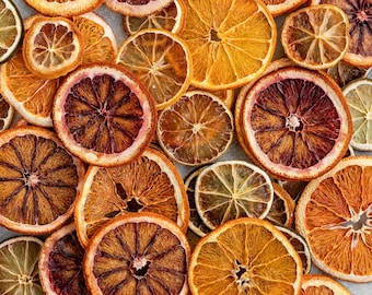 May include: A collection of dried citrus fruit slices, including oranges, lemons, and blood oranges. The slices vary in size and color, ranging from bright orange to deep reddish-brown, with some green and yellow hues. The arrangement is scattered and overlapping.