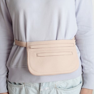 Pode incluir: Uma pochete de couro rosa claro com um bolso com z&iacute;per e um cinto.