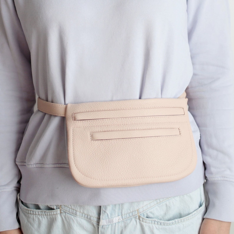 Pode incluir: Uma pochete de couro rosa claro com um bolso com z&iacute;per e um cinto.