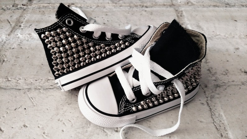 May include: A pair of black high-top sneakers with silver studs covering the entire shoe.