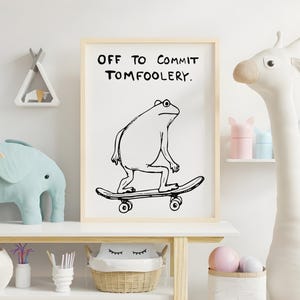 May include: A framed print with the text "OFF TO COMMIT TOMFOOLERY" above a cartoon frog on a skateboard. The artwork is in black and white, set against a white background. The room features decorative items like a giraffe and elephant.