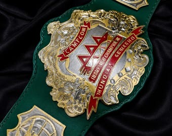 Puede incluir: Un cinturón de campeonato de lucha libre con una correa de cuero verde oscuro y una gran placa central ornamentada en oro y plata. La placa muestra el texto AAA, CAMPEON y HEAVYWEIGHT CHAMPION MUNDIAL GENERATION, con cintas rojas.