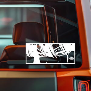 May include: A white vinyl decal featuring a stylized anime character with spiky hair and the word "HEH" in a speech bubble. The decal is rectangular and designed to be applied to a car window.