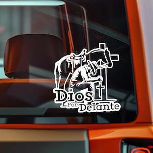 May include: White vinyl decal featuring a cowboy kneeling before a cross, with a horse and saddle in the background. The text "Dios Por Delante" is displayed below the image.