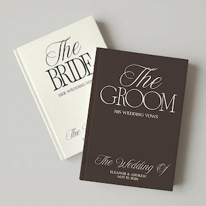 Op de afbeelding: Twee hardcover boeken met huwelijksgeloften. Het witte boek heeft zwarte tekst met The Bride Her Wedding Vows. Het donkerbruine boek heeft witte tekst met The Groom His Wedding Vows, The Wedding Of, Eleanor & Andrew, 10 mei 2026.