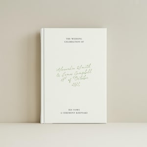 May include: A white hardback book featuring black and green text. The cover displays the words THE WEDDING CELEBRATION OF, Alexandra Smith & James Campbell 10th of October 2027, HIS VOWS, and A CEREMONY KEEPSAKE. The names and date are in green cursive.
