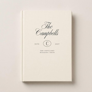 May include: A cream-colored hardcover book with black text that reads The Campbells, ESTD, 2027, with a letter C inside an oval, and the text THE OFFICIANT Alexander Smith printed on the front cover in a clean, centered layout.
