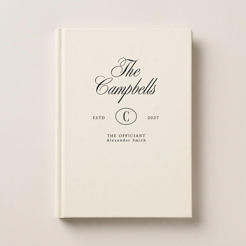 May include: A cream-colored hardcover book with black text that reads The Campbells, ESTD, 2027, with a letter C inside an oval, and the text THE OFFICIANT Alexander Smith printed on the front cover in a clean, centered layout.