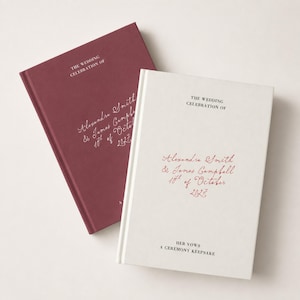 May include: Two hardback books, one burgundy and one white, featuring the text "THE WEDDING CELEBRATION OF" and "Alexandra Smith & James Campbell 10th of October 2027" in elegant script. The white book also includes "HER VOWS A CEREMONY KEEPSAKE".