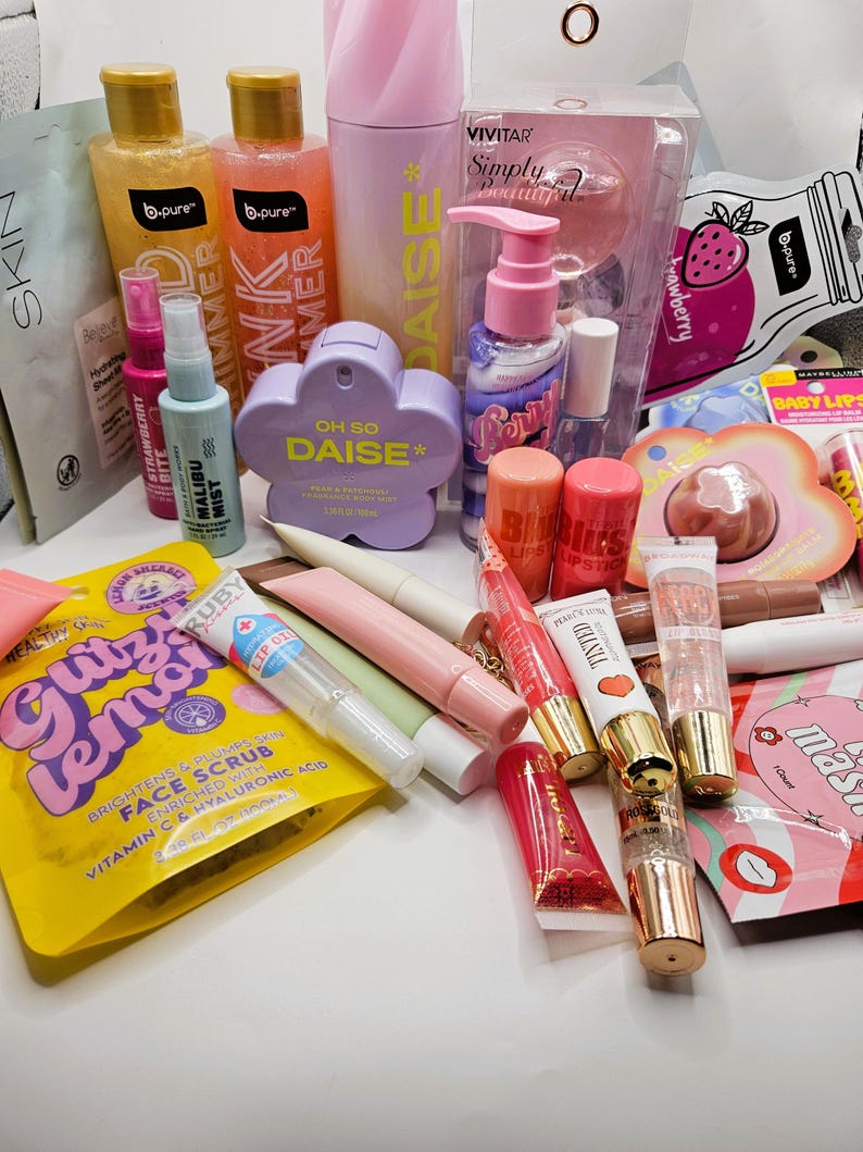 May include: A collection of beauty and skincare products including b.pure shimmer gels, a Vivitar Simply Beautiful set, Oh So Daise fragrance mist, various lip glosses, lipsticks, face masks, and a Gitz Lemon face scrub packet with hyaluronic acid.